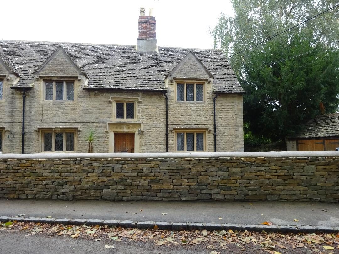 Rebuilt dry stone boundary wall in front of historic Cotswold almshouses
