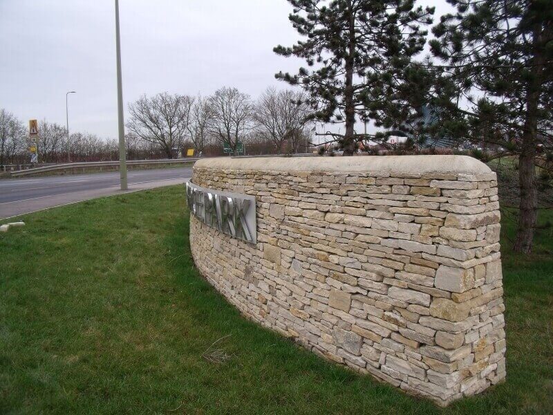 Curved dry stone entrance wall with inset signage near Bicester