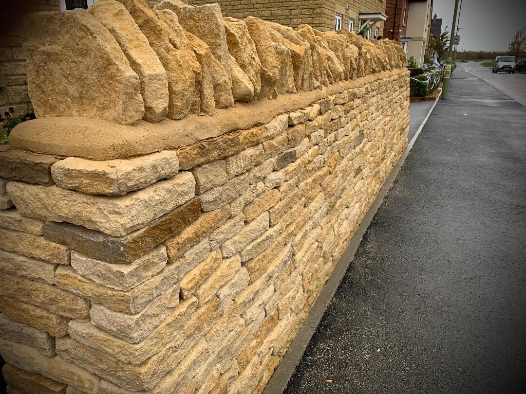New Cotswold limestone boundary wall with upright coping stones, Carterton