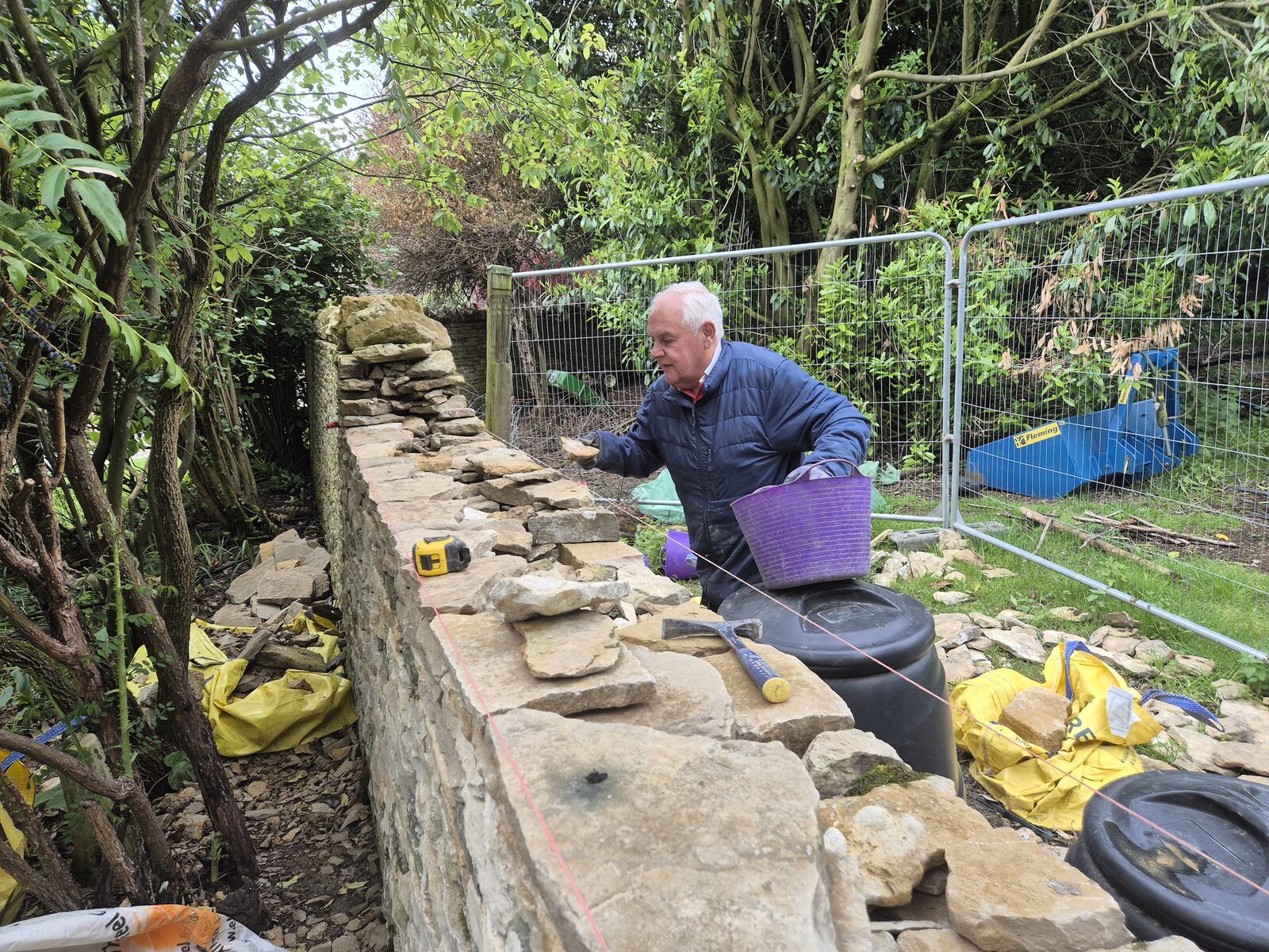 Dry stone waller placing stone on garden wall during rebuild