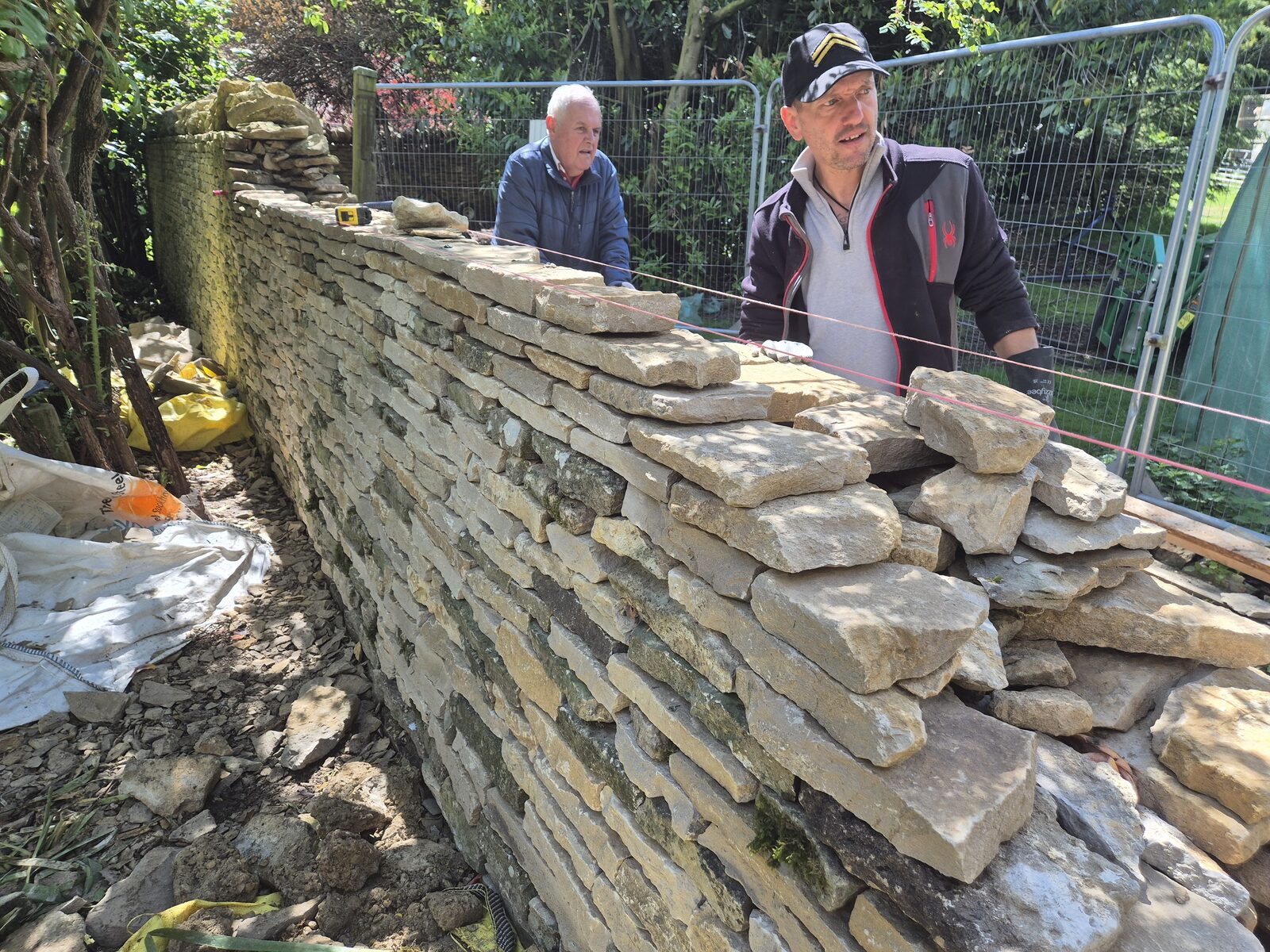 Two dry stone wallers building the top courses of a garden wall