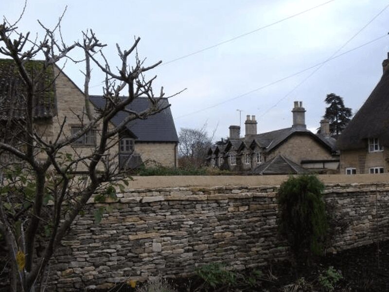 Dry stone estate wall alongside traditional Cotswold cottages, Middleton Stoney