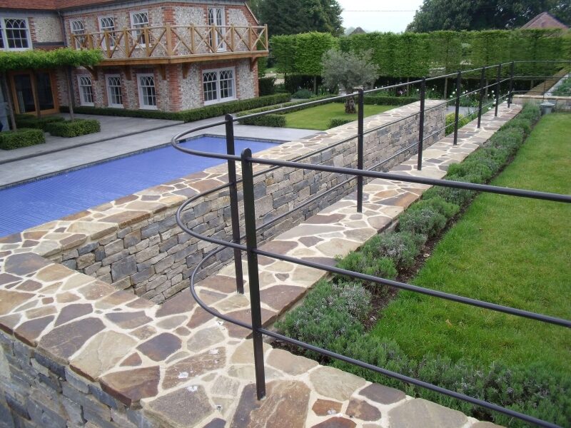 Curved dry stone wall beside pool with flagstone coping and planting