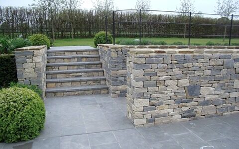 Stone steps between dry stone retaining walls in a landscaped garden