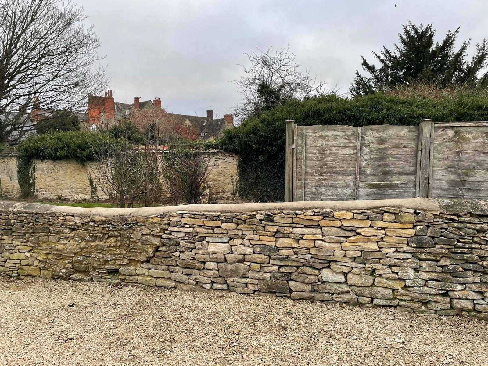 Repaired dry stone wall section with new stone blended into weathered wall